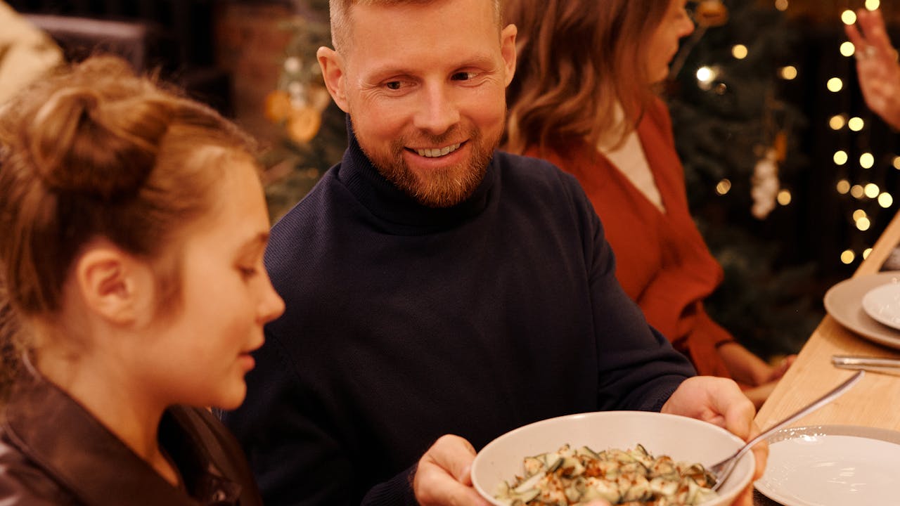 A smartphone wrapped in a bow sitting under a holiday tree.